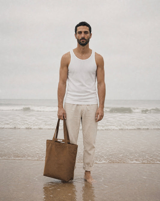 Man holding a brown bag on a beach with ocean in the background